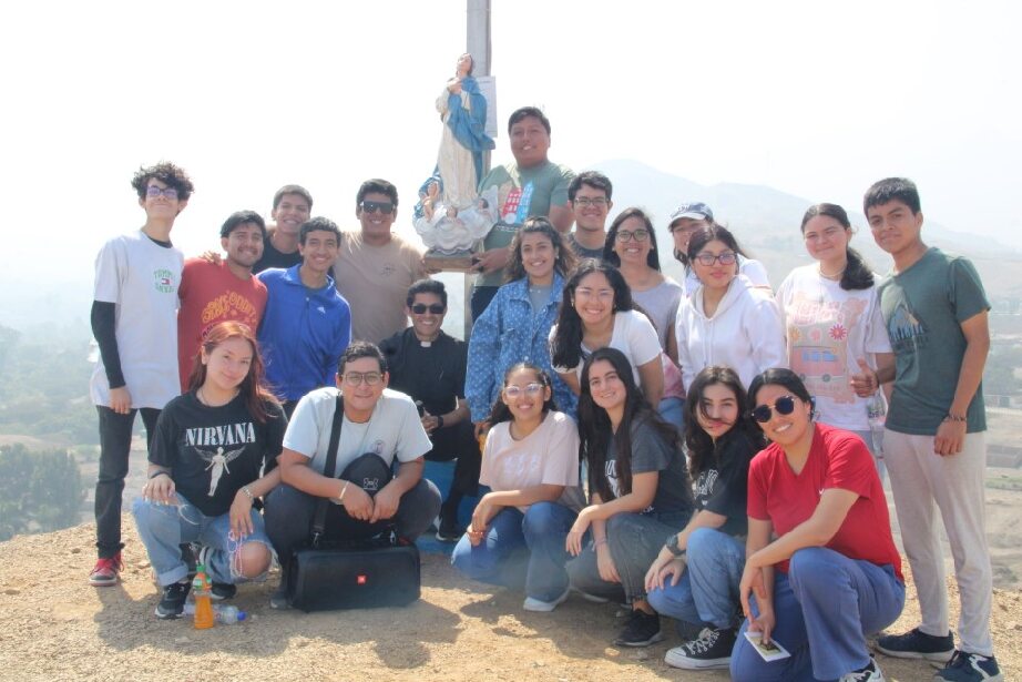 Un grupo de jóvenes durante una peregrinación mariana posan felizes en la cima de una montaña. 