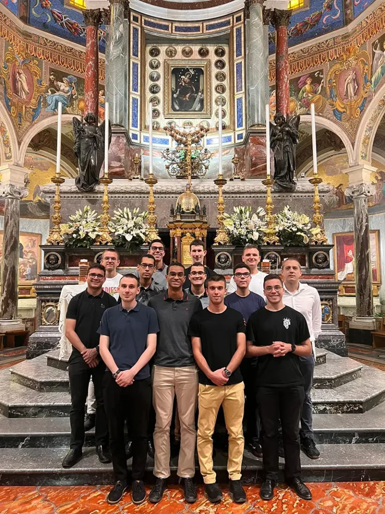 Guilheme szemináriumi osztálytársaival pózol egy templomban, az oltárral a háta mögött.