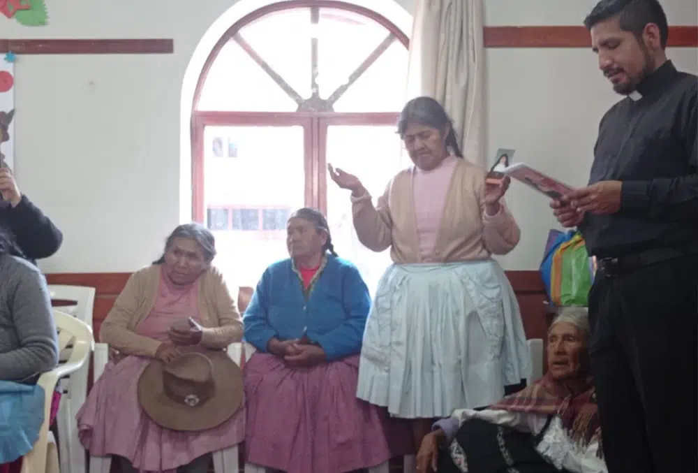 Padre Christiam Burgos rezando con fieles en una comunidad andina del Per&uacute;.